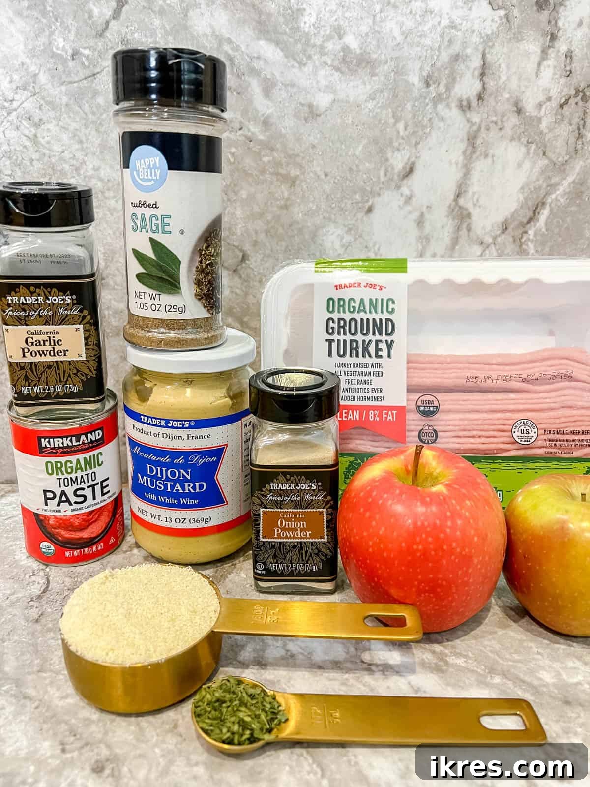 A collection of fresh ingredients laid out for healthy turkey apple meatloaf preparation, including ground turkey, apples, onion, and various spices.