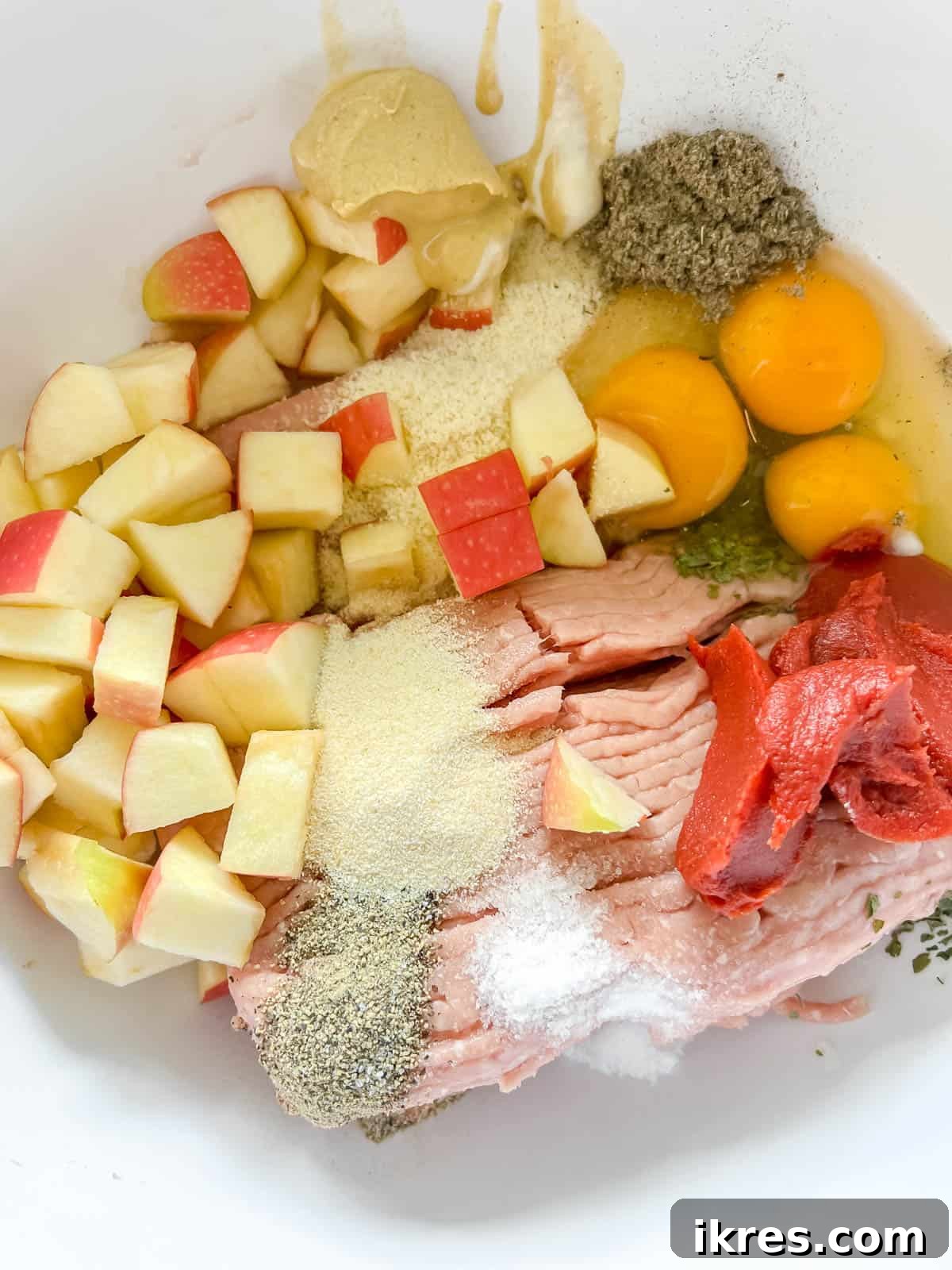 All the meatloaf ingredients, including ground turkey, diced apples, and spices, combined in a large mixing bowl.