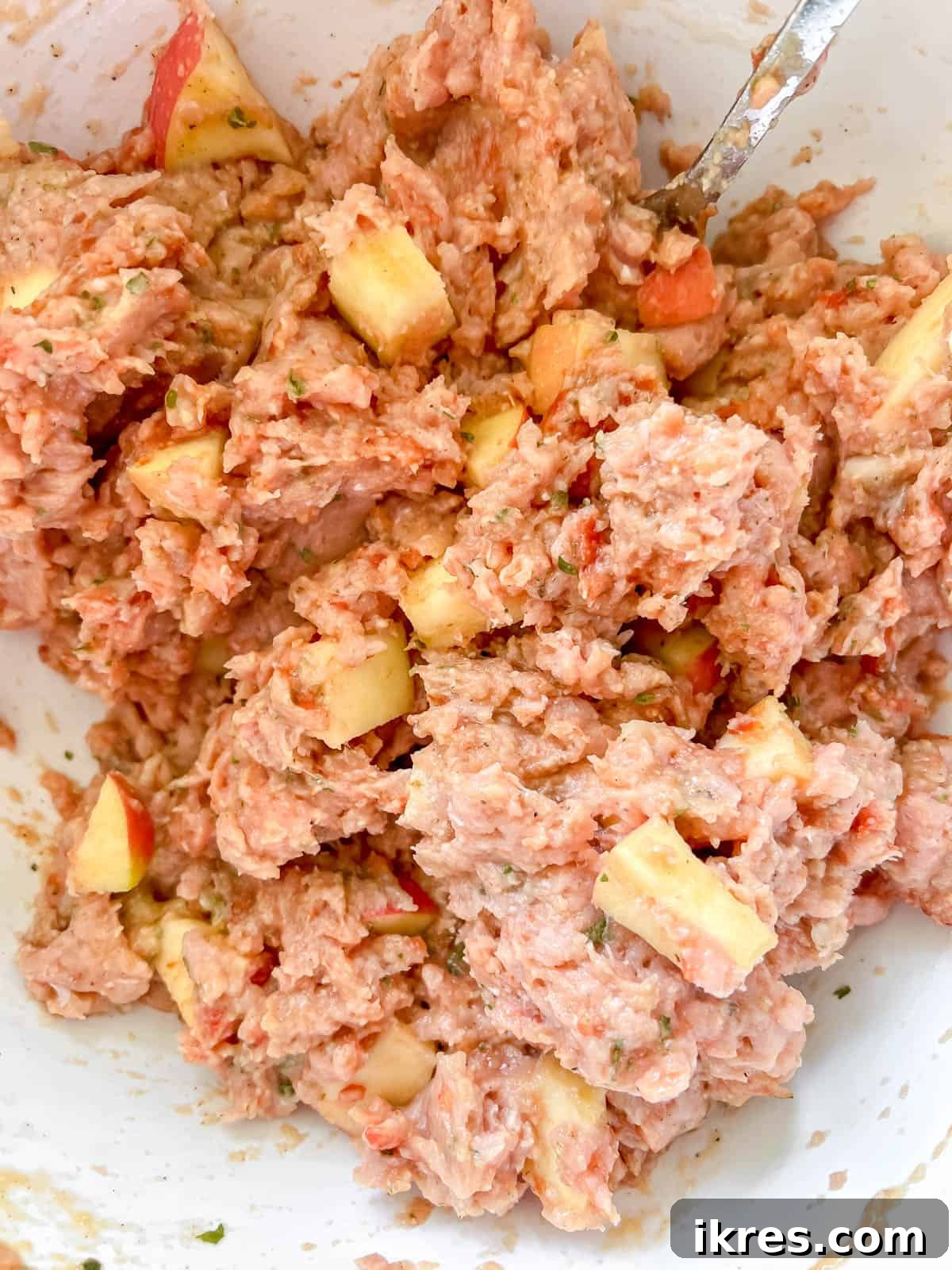 Meatloaf ingredients being thoroughly mixed by hand in a large bowl to ensure even distribution of flavors.