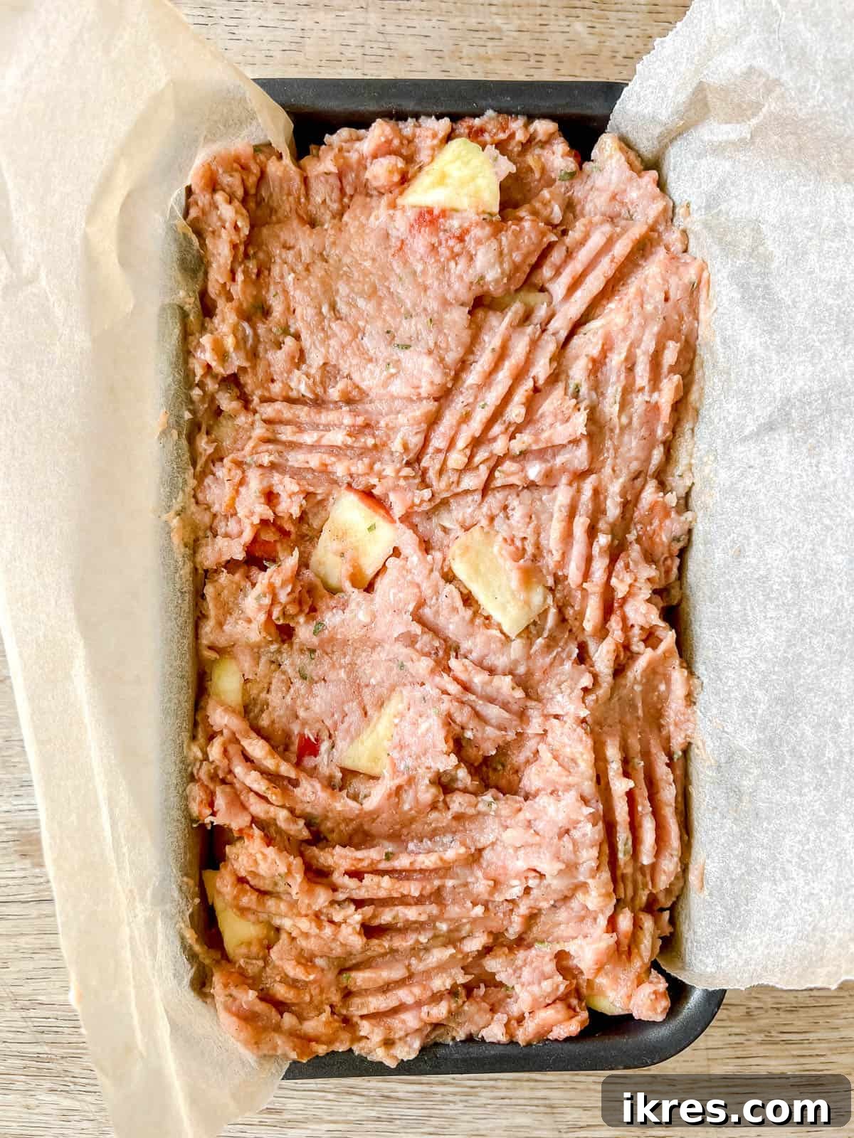 Unbaked meatloaf mixture pressed into a parchment-lined loaf tin, ready for the oven.