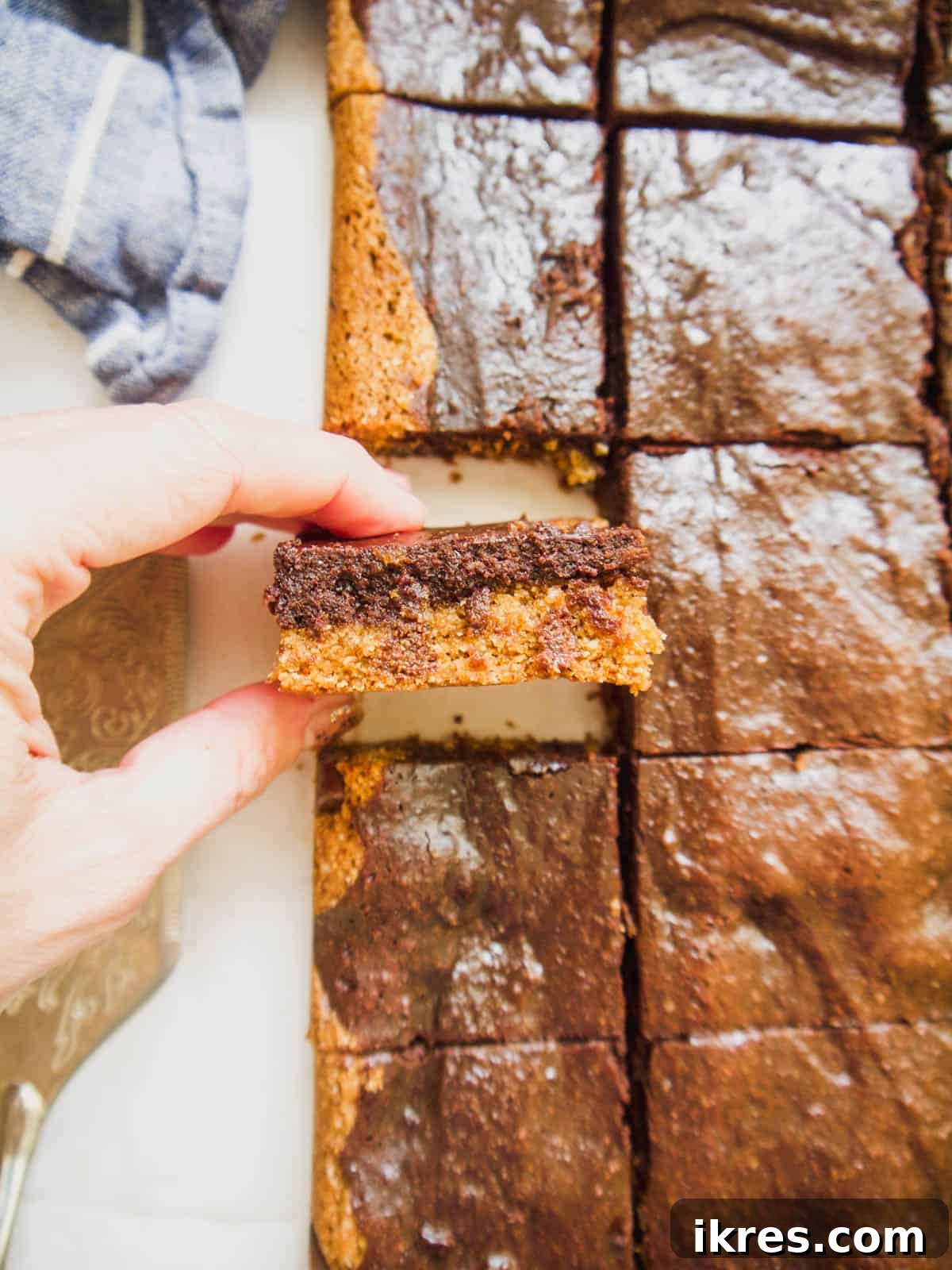 A perfectly baked healthy brookie bar held in hands, showcasing its distinct cookie and brownie layers.