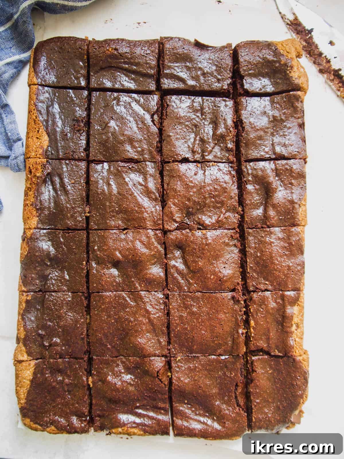 Close-up of a knife cutting baked Paleo brownie cookie bars into uniform cubes.