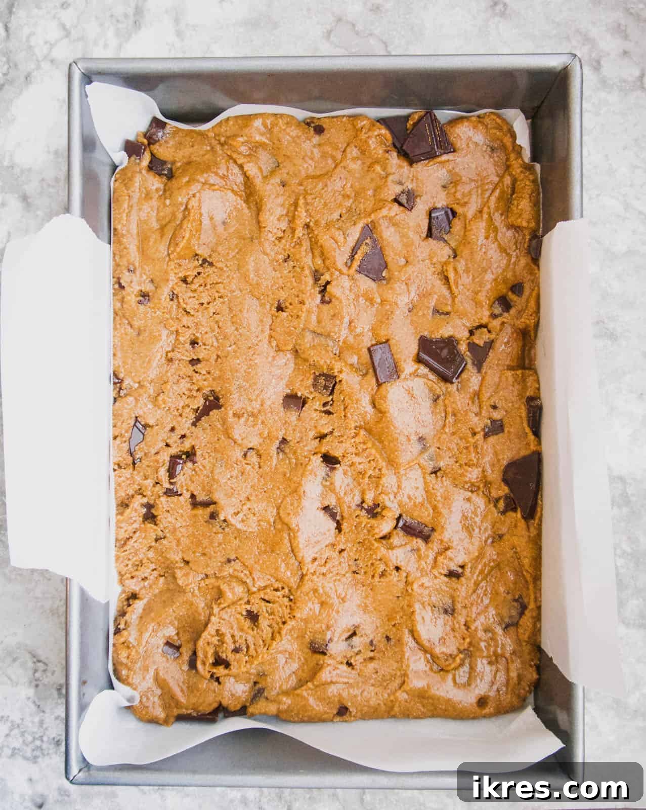 The prepared cookie bar layer pressed evenly into a baking pan.