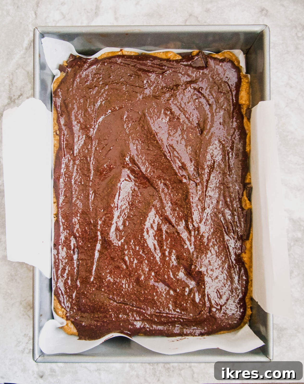 Raw brookie layers smoothed out in the pan, ready for the oven.