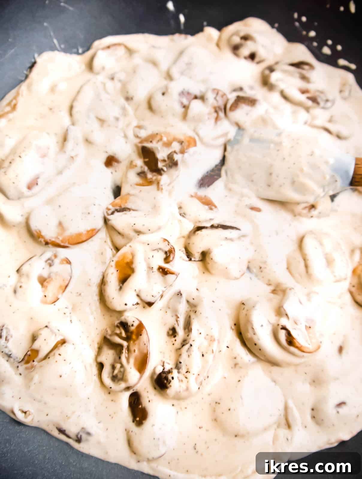 Pillowy Cauliflower Gnocchi with Velvety Mushroom Cream 5 Coconut cream and black pepper being added to the browned mushrooms in a frying pan to create the sauce.