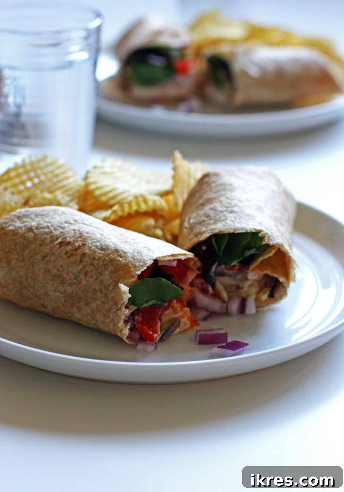Loaded Ranch Chicken Wraps 5 Two plates of chicken ranch wraps, garnished with fresh onions, iceberg lettuce, tomatoes, and served with potato chips.