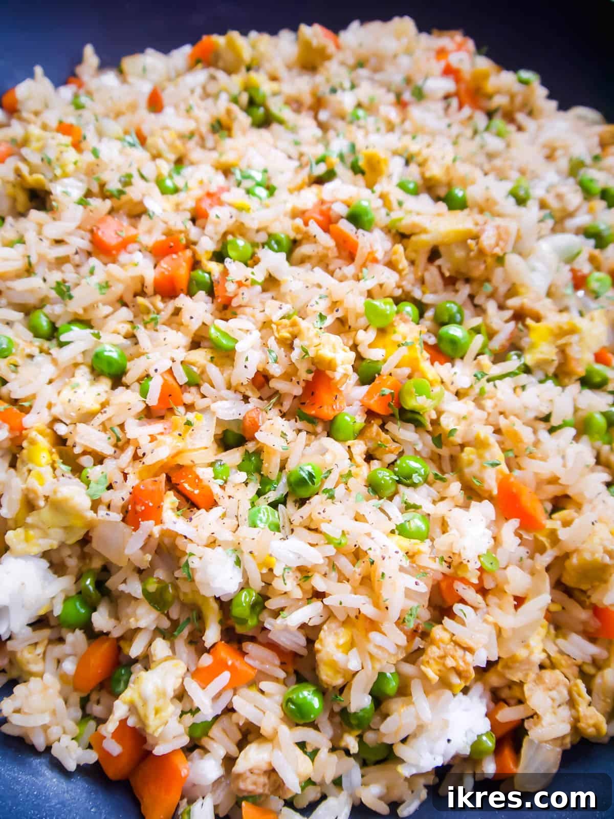 The finished coconut aminos fried rice, rich with vegetables and eggs, is perfectly cooked and evenly seasoned within the frying pan, ready to be served.