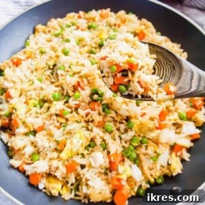 A top-down view of a small bowl filled with savory Coconut Aminos Fried Rice, garnished with fresh green onions and sesame seeds.