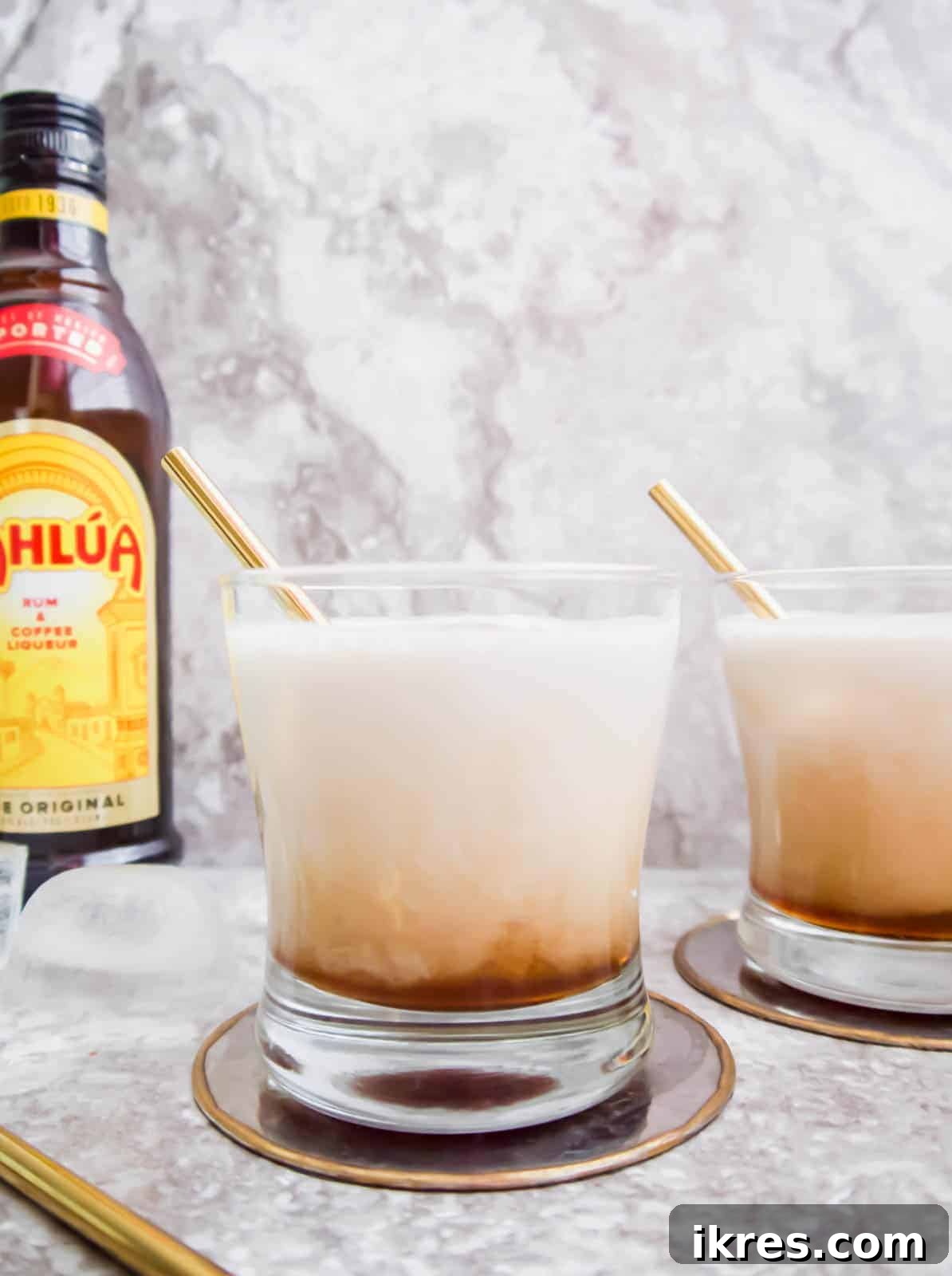 Silken White Russian 2 A glass of creamy dairy-free White Russian cocktail with a golden straw, garnished with coffee beans.