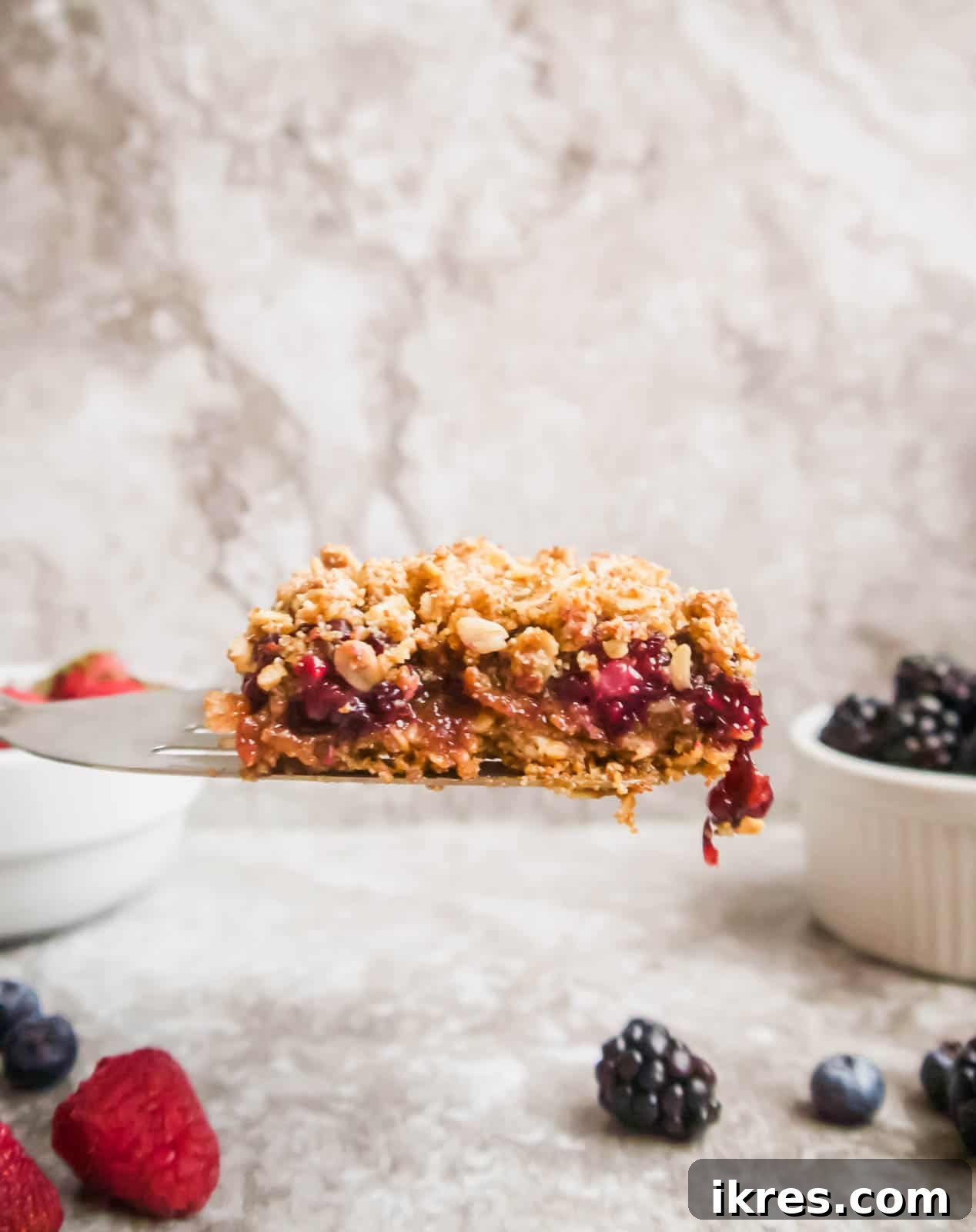 Delicious Gluten-Free Dairy-Free Berry Oat Bars 3 A slice of a berry oat bar being carefully lifted from the baking pan, revealing its layered texture.