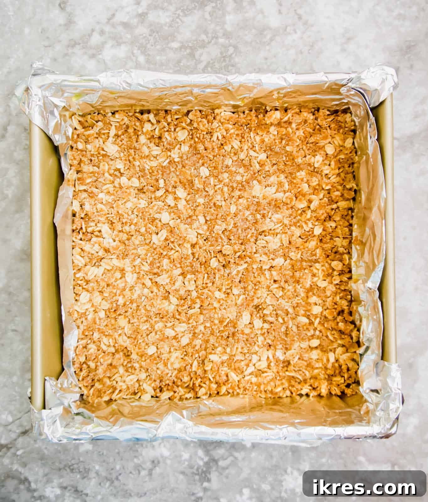 Delicious Gluten-Free Dairy-Free Berry Oat Bars 5 The base oat layer of the berry oatmeal bars pressed into a baking pan.