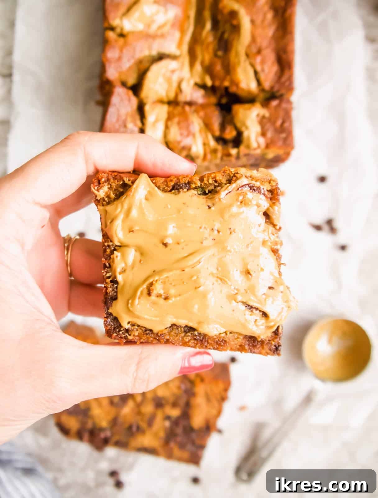 A close-up shot of the top of baked paleo banana bread, showing the rich, golden-brown crust and visible swirls of sunflower butter.