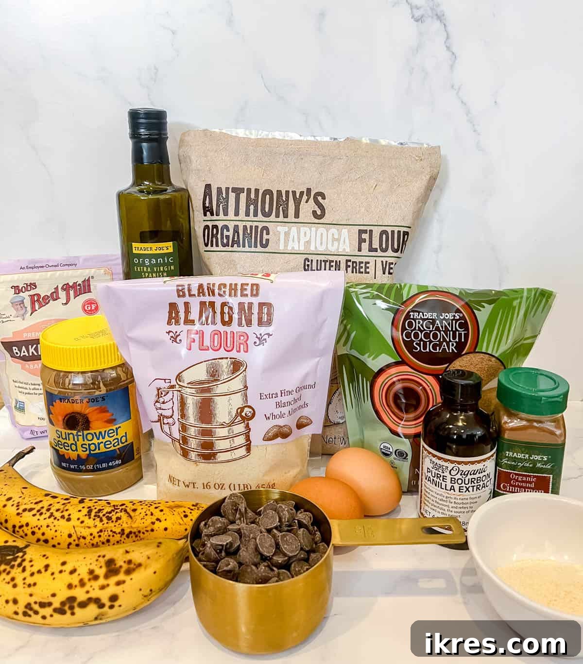 All the ingredients neatly laid out on a white surface, ready to be combined for making paleo chocolate chip banana bread with sunflower butter.