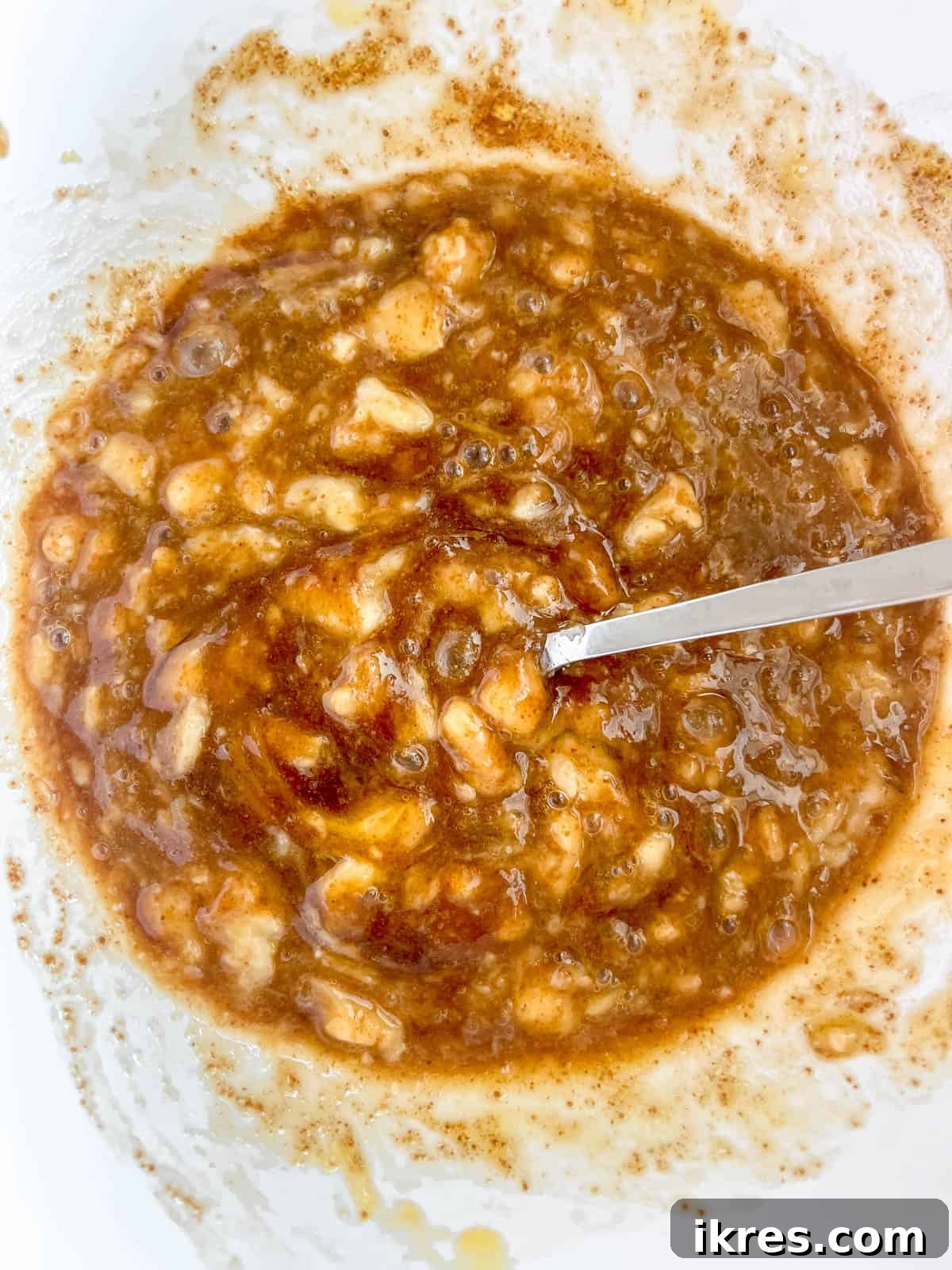 Mashed ripe bananas being added to the bowl of wet ingredients.