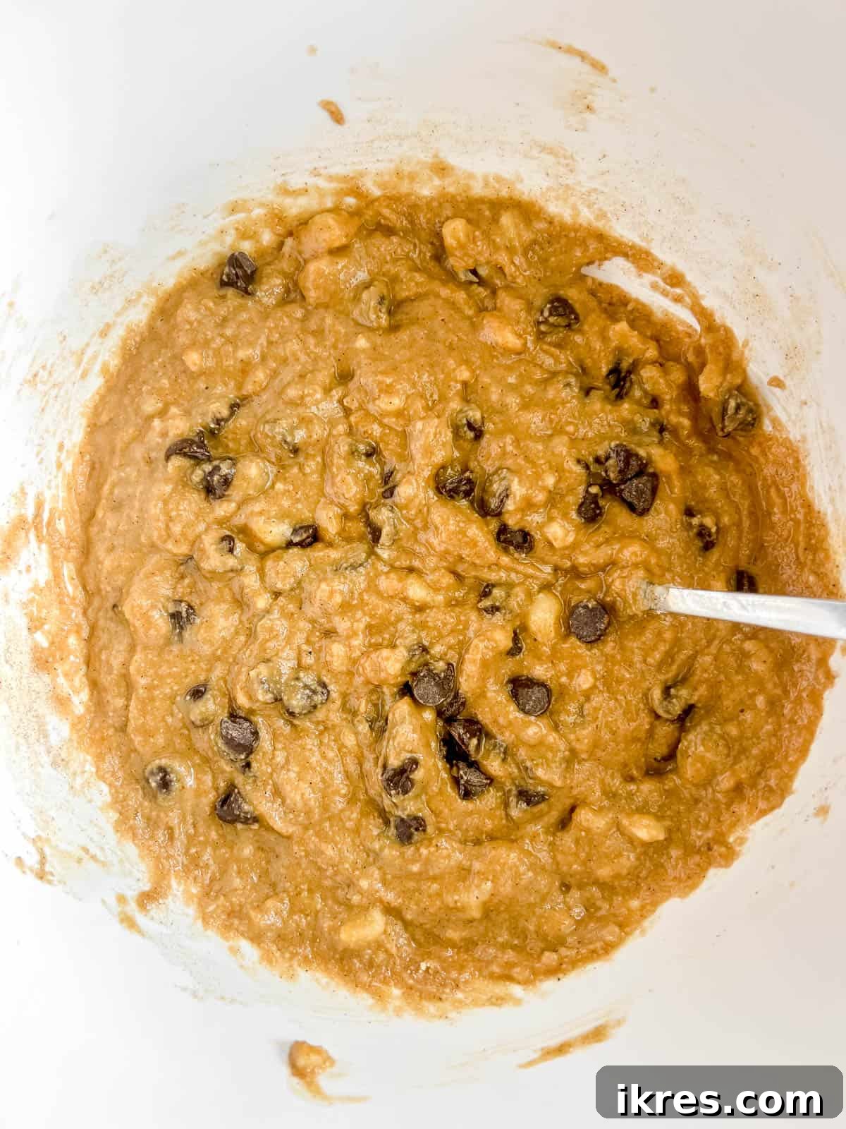 The combined wet and dry ingredients in a bowl, with chocolate chips folded in, forming the banana bread batter.