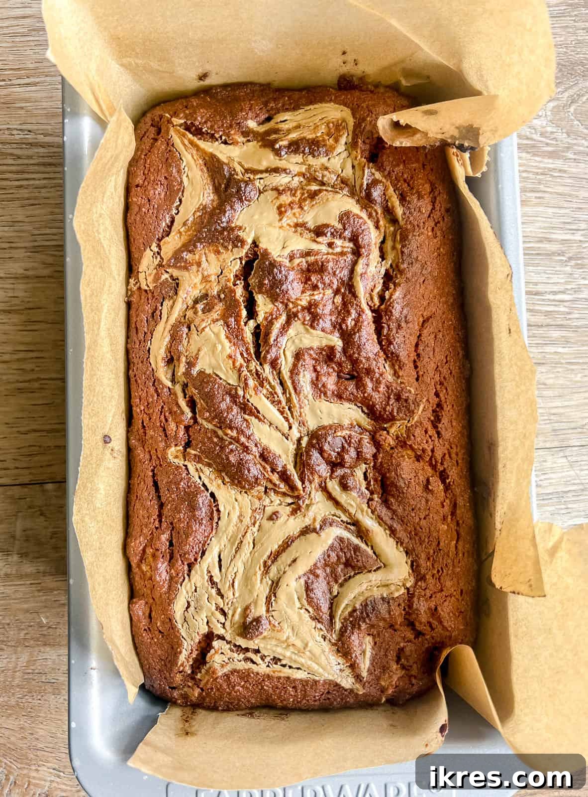A freshly baked loaf of sunflower butter and chocolate chip banana bread, golden brown and perfectly risen, cooling on a wire rack.