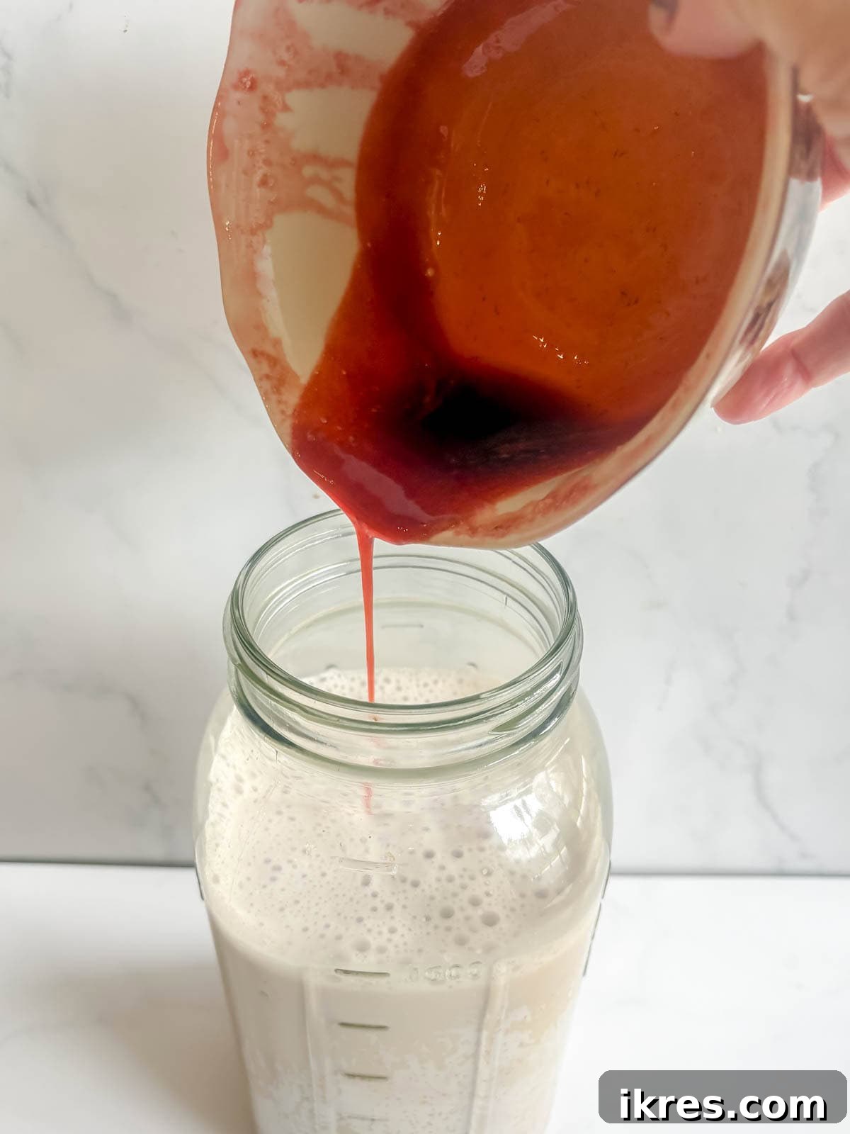 Homemade Vegan Strawberry Almond Milk 13 Pouring the homemade strawberry syrup into the freshly strained almond milk.