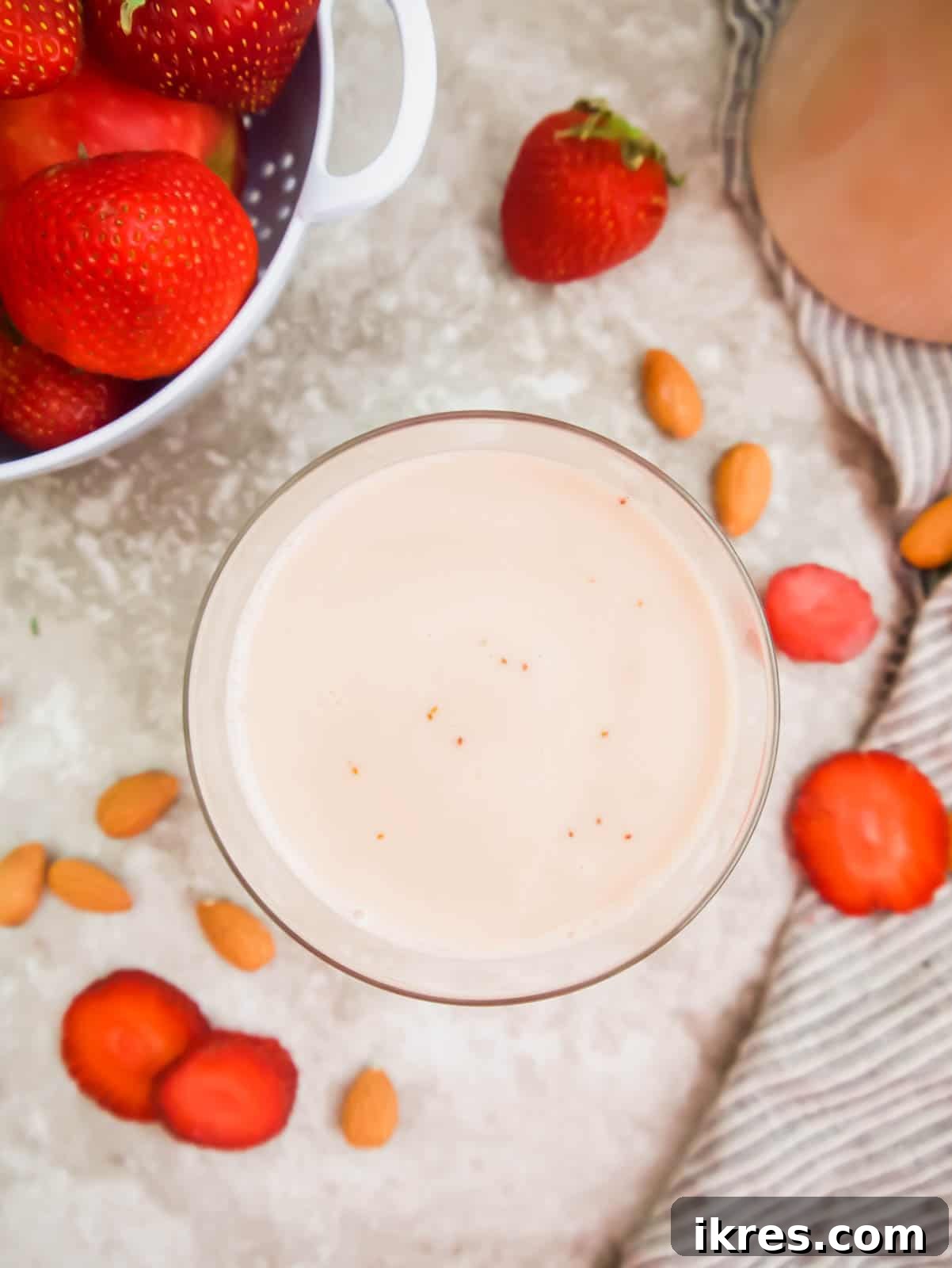 Homemade Vegan Strawberry Almond Milk 15 A glass of homemade strawberry almond milk garnished with fresh strawberries, showcasing its natural pink color.