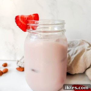 Homemade Vegan Strawberry Almond Milk 16 Strawberry almond milk in a mason jar, garnished with fresh berries.