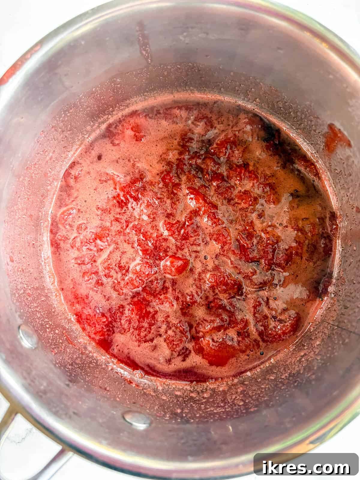 Homemade Vegan Strawberry Almond Milk 5 Strawberries simmering in a pot, softening and forming a syrup.