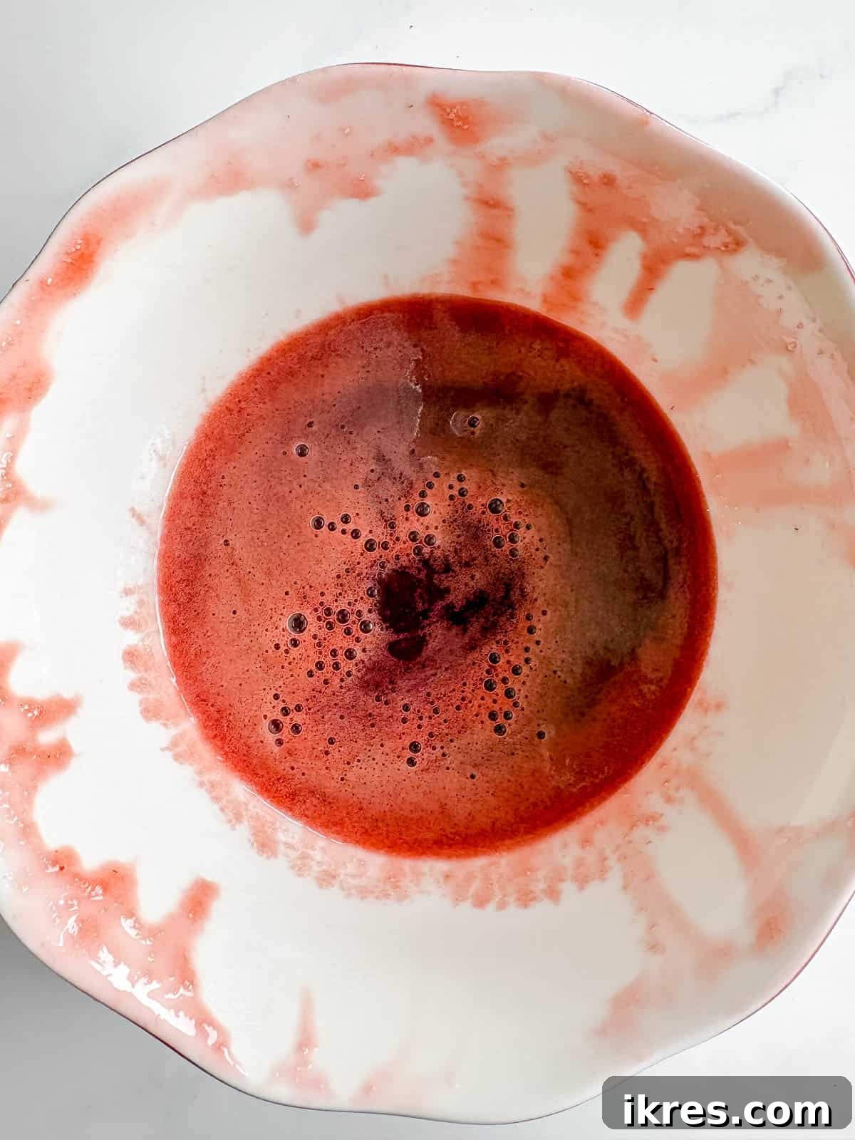 Homemade Vegan Strawberry Almond Milk 7 Clear, vibrant strawberry syrup collected in a small bowl.