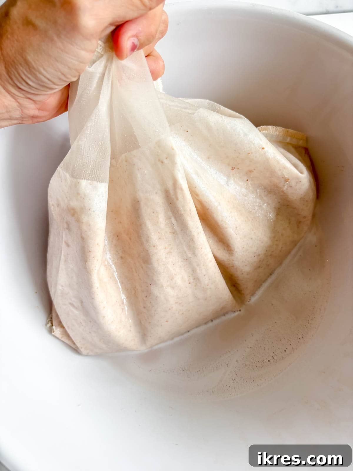 Homemade Vegan Strawberry Almond Milk 10 Blended almond and strawberry mixture poured into a nut milk bag set in a large bowl.