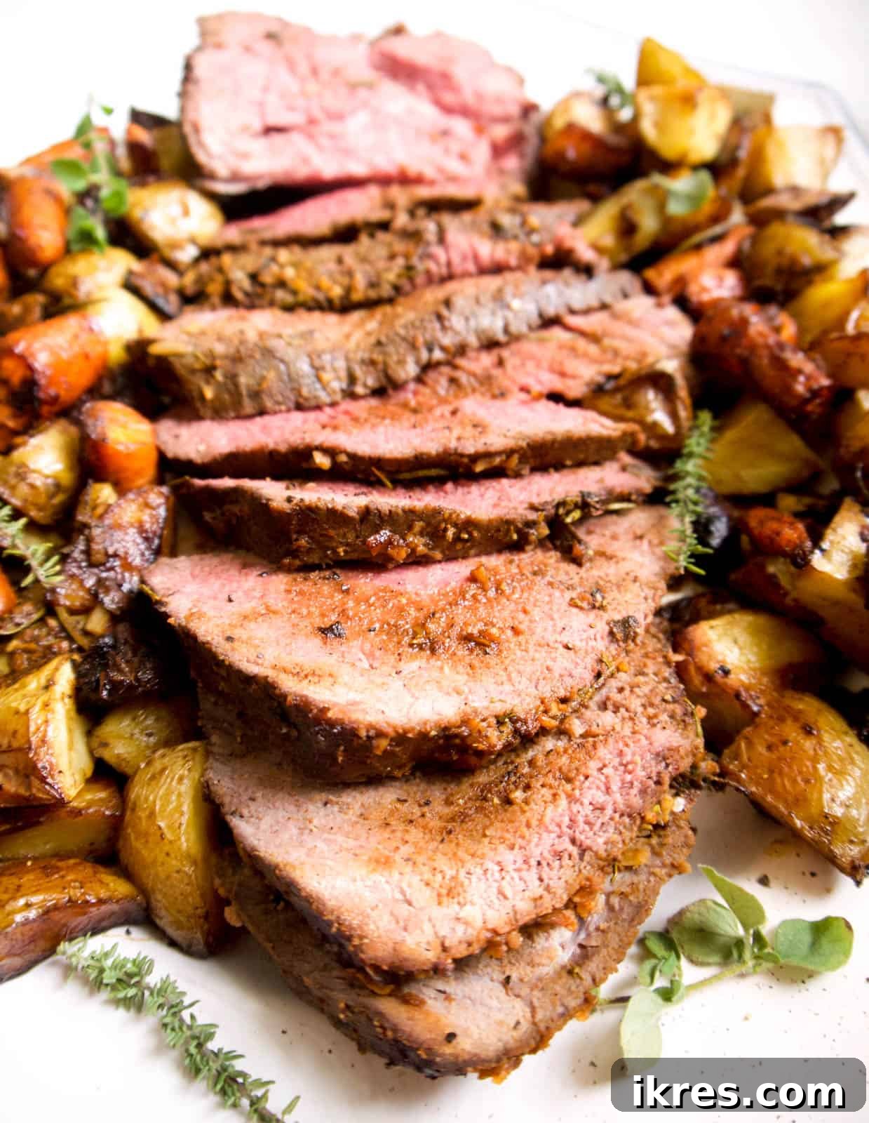 Savory Garlic Herb Shoulder Roast 3 Perfectly cooked slices of clod roast artfully arranged on a pristine white plate, showcasing its tender texture.