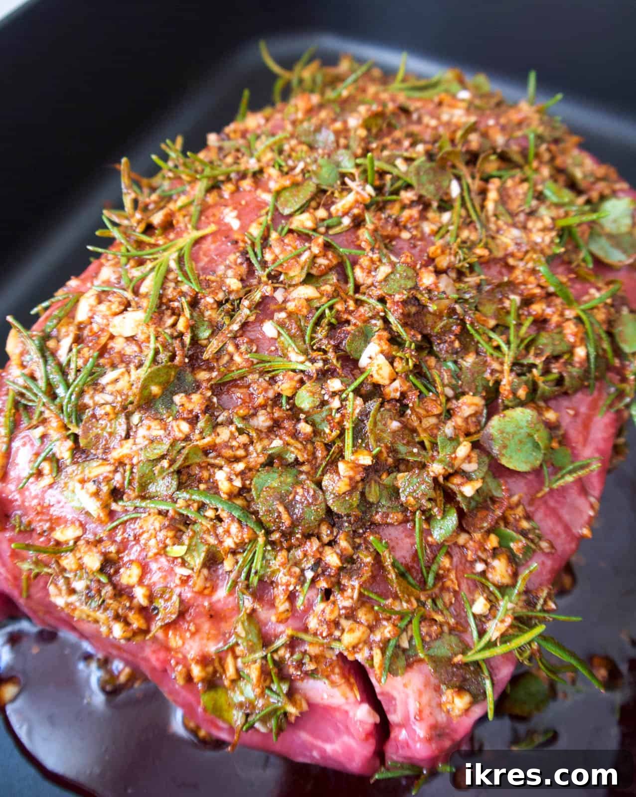 Savory Garlic Herb Shoulder Roast 5 A raw heart of clod roast, generously coated in the aromatic garlic and herb paste, nestled in a roasting pan.
