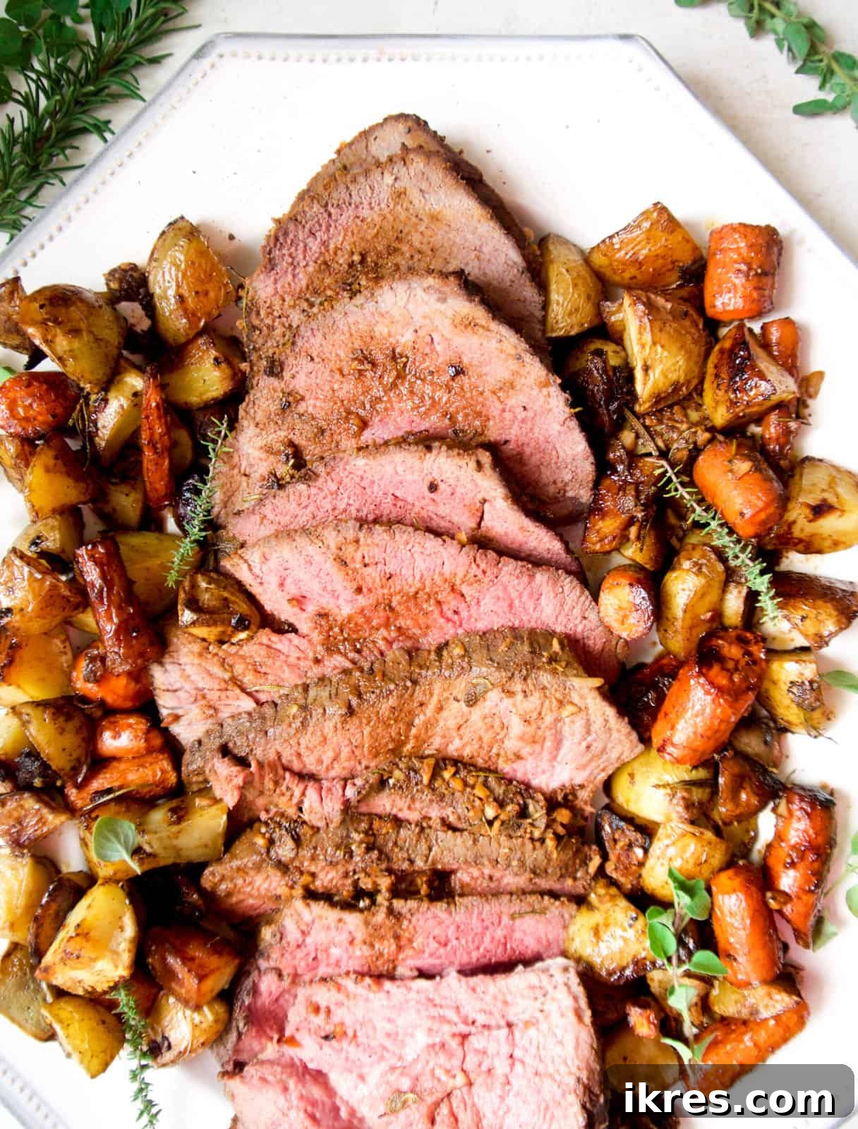 Savory Garlic Herb Shoulder Roast 9 Succulent slices of shoulder clod roast beautifully presented on a plate, surrounded by golden roasted potatoes and carrots.
