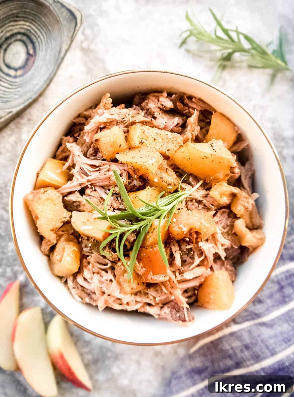 Fall-Apart Apple Pulled Pork 2 A generous serving of succulent apple pulled pork in a rustic bowl, garnished with tender cooked apple pieces on top, ready to be enjoyed.