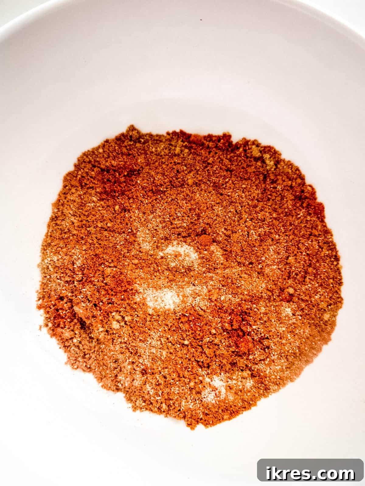 Fall-Apart Apple Pulled Pork 4 A bowl filled with a blend of dried spices, including cinnamon, paprika, and rubbed sage, essential for seasoning the apple juice pulled pork.