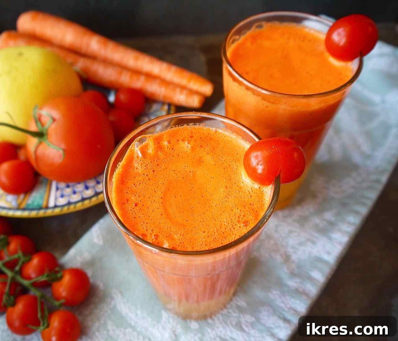 Side angle view of vibrant orange tomato carrot juice served in two elegant glasses.