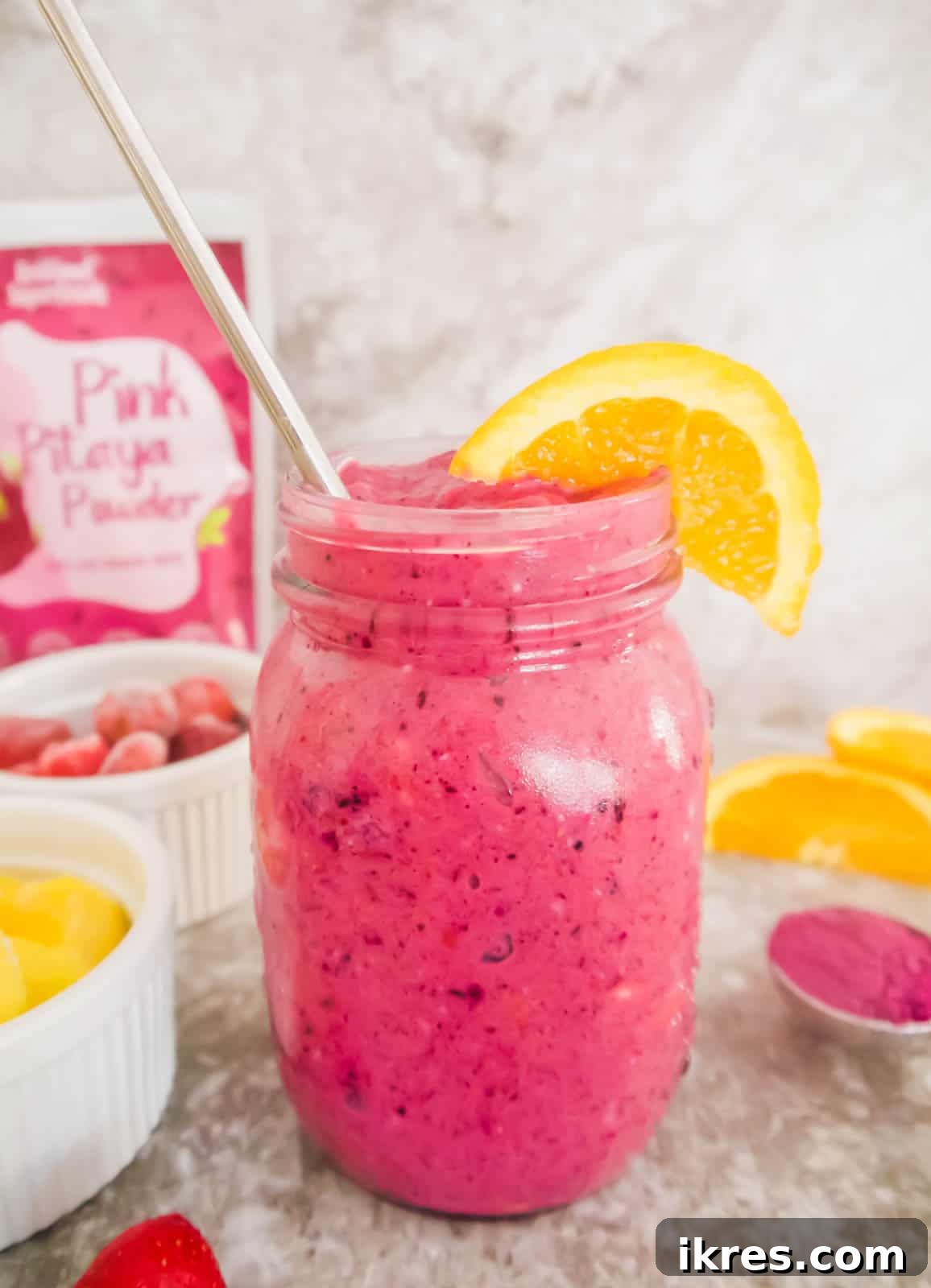 A refreshing mango dragonfruit smoothie poured into a mason jar, garnished with fresh fruit, ready to be enjoyed.