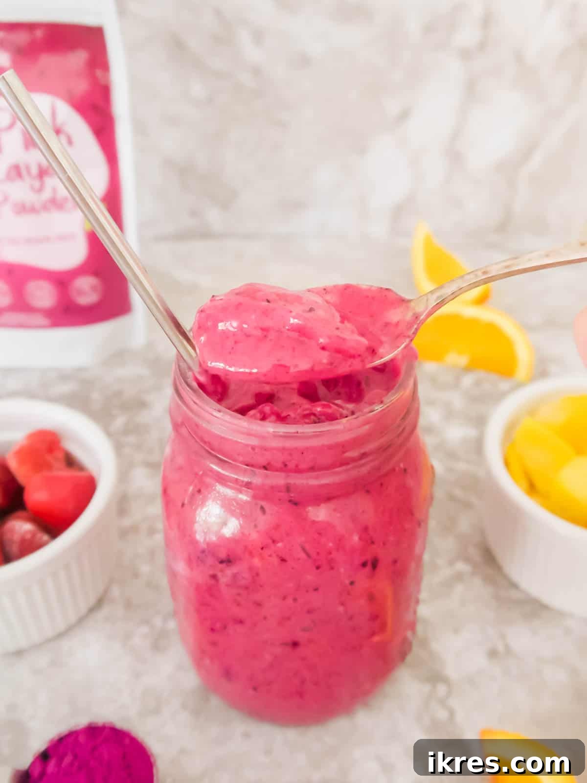 A spoonful of the creamy, pink mango dragon fruit smoothie being scooped out, showcasing its rich texture.