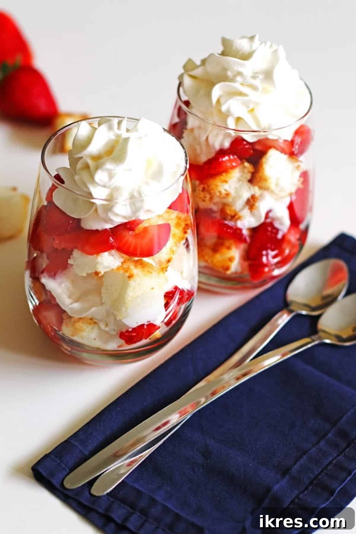 Strawberry Angel Delight 2 Two glasses of angel food cake strawberry shortcake topped with whipped cream.
