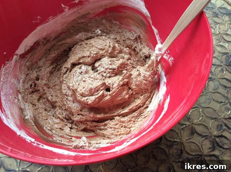 Decadent Chocolate Mousse Bites 5 A creamy, smooth mixture of melted chocolate and Cool Whip, blended together in a white bowl, showing the nascent stage of the chocolate mousse base.
