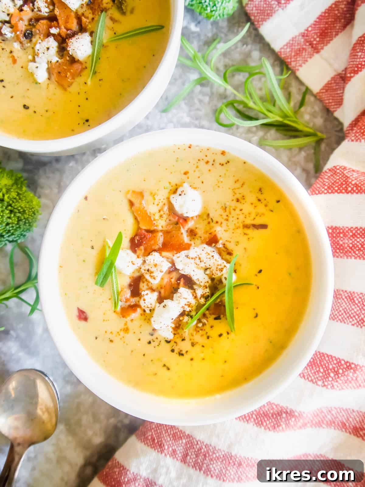 Broccoli and sweet potato soup, garnished with creamy coconut milk swirls, served in two bowls.