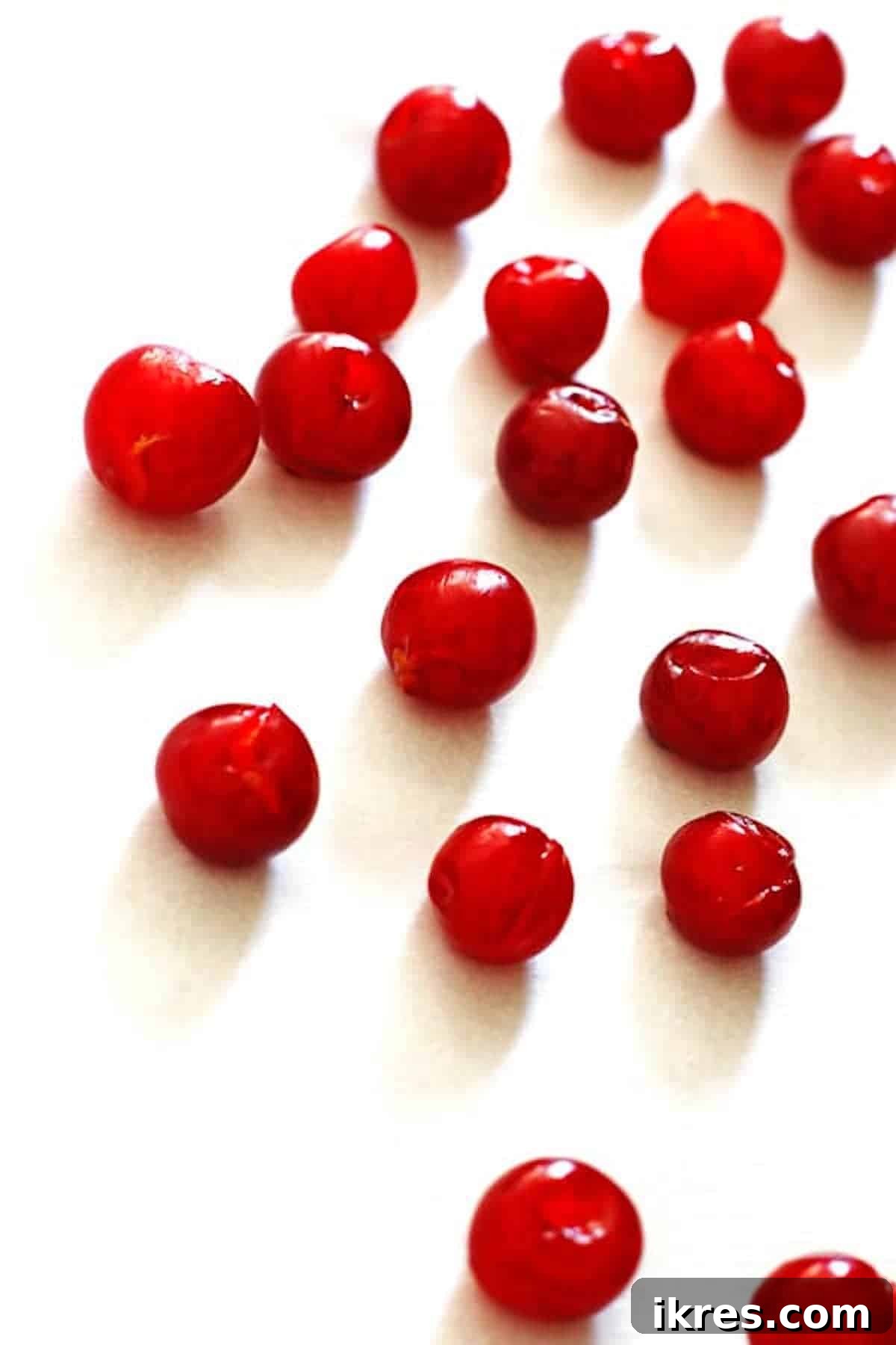 Tropical Cherry Pineapple Bliss 6 Pitted tart cherries evenly spread in a single layer on a baking sheet covered with white parchment paper, ready for freezing.