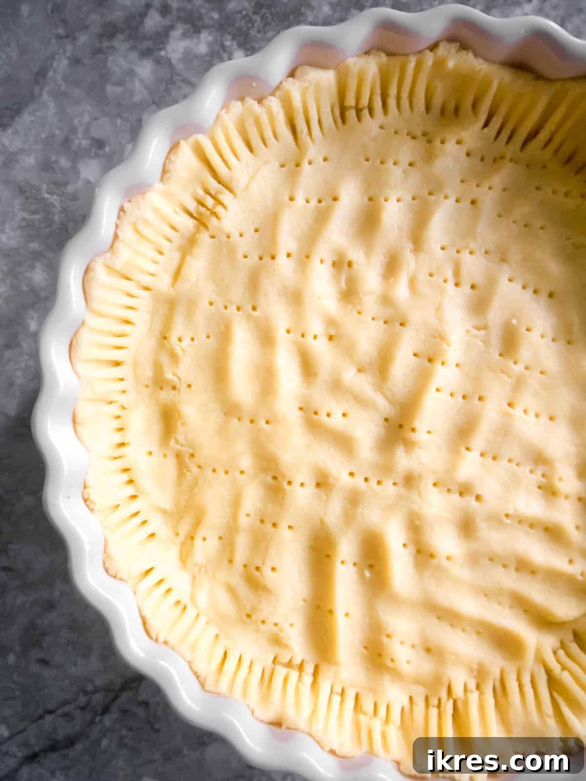 Raw dough spread out evenly in tart pan with holes poked.