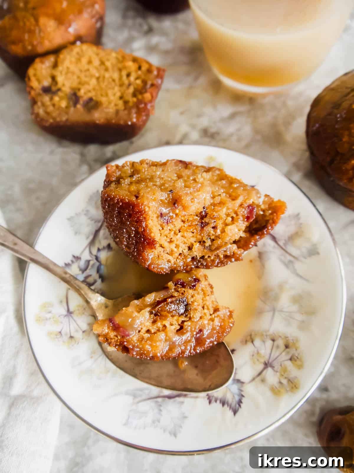 Decadent Gluten-Free Dairy-Free Sticky Toffee Muffins 2 Gluten-free sticky toffee pudding muffin on a plate with a bite taken out of it, showing its moist, date-filled interior.