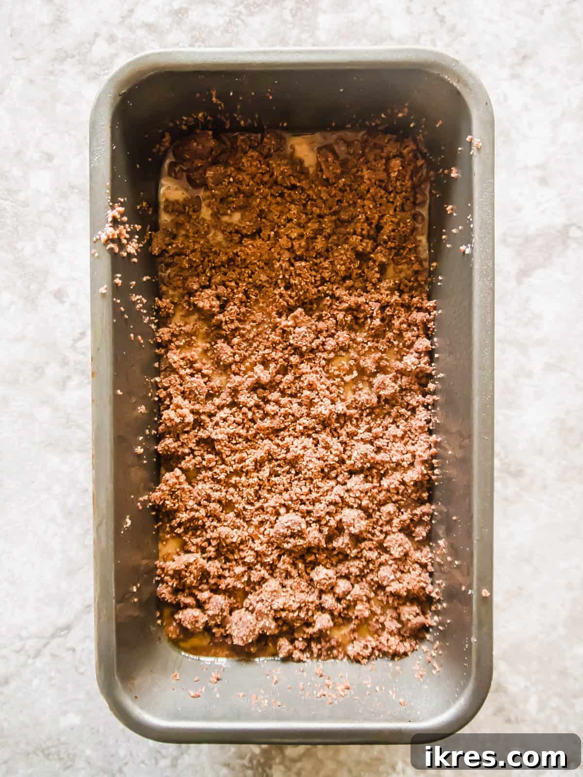 Paleo Gluten-Free Cinnamon Swirl Banana Bread Coffee Cake 5 Banana bread coffee cake batter in a loaf tin with the first streusel layer on top.