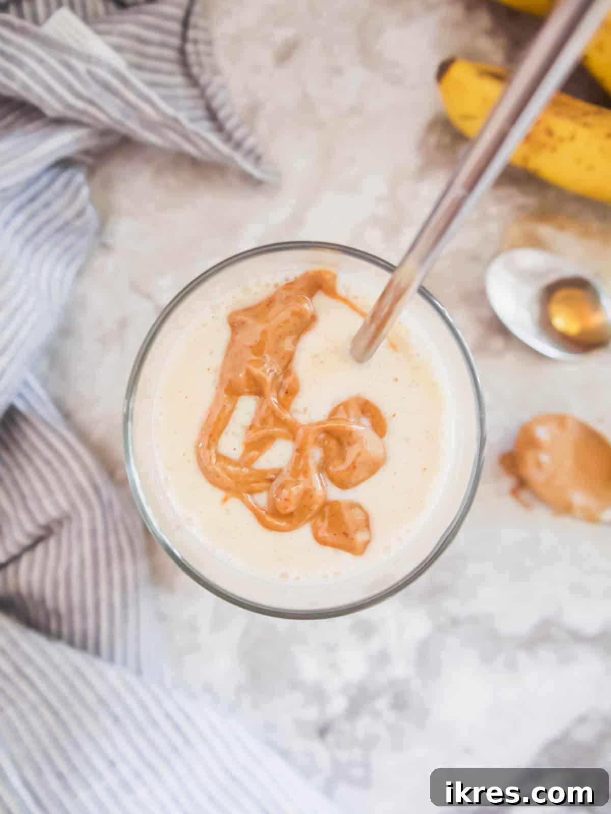 A beautifully presented maple syrup smoothie in a glass, with an artful drizzle of almond butter on top, highlighting its rich and creamy consistency.