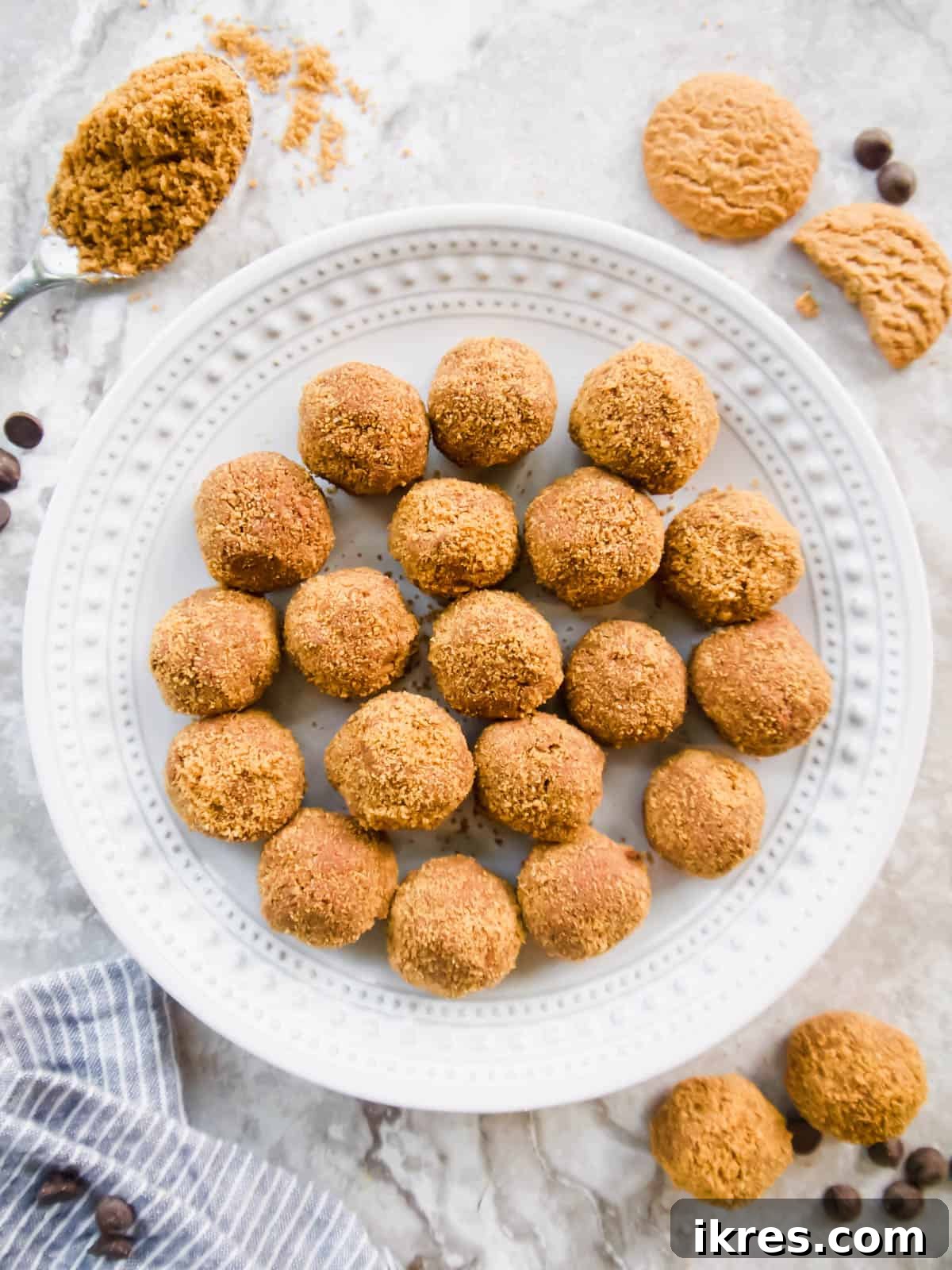 Decadent Gluten-Free Dairy-Free Chocolate Mousse Truffles 2 Decadent Dairy-Free Chocolate Mousse Balls, garnished with chocolate shavings and cookie crumbs, resting on a white plate. A festive background hints at a holiday gathering, showcasing extra cookies and chocolate for ambiance.