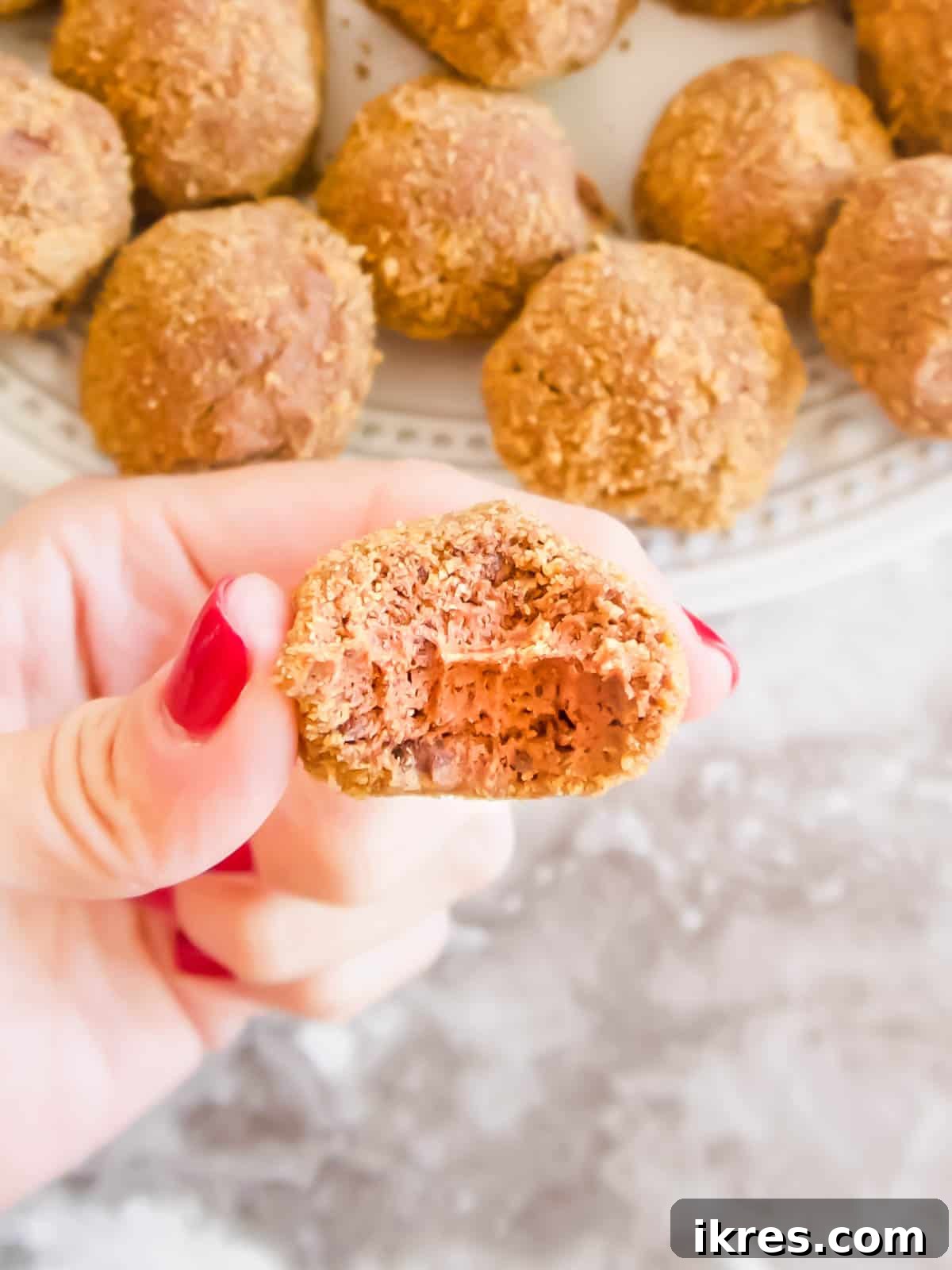 Decadent Gluten-Free Dairy-Free Chocolate Mousse Truffles 9 An inviting close-up of a Dairy-Free Chocolate Mousse Ball with a bite taken out, revealing its creamy, dark chocolate interior and textured cookie crust.