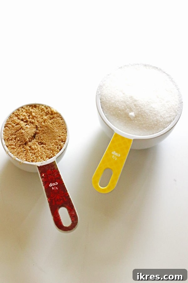 Toasted Smores Cookies 4 Two measuring cups, one filled with light brown sugar and the other with white granulated sugar, are meticulously prepared and ready for use, emphasizing the importance of precise ingredient measurement in baking.