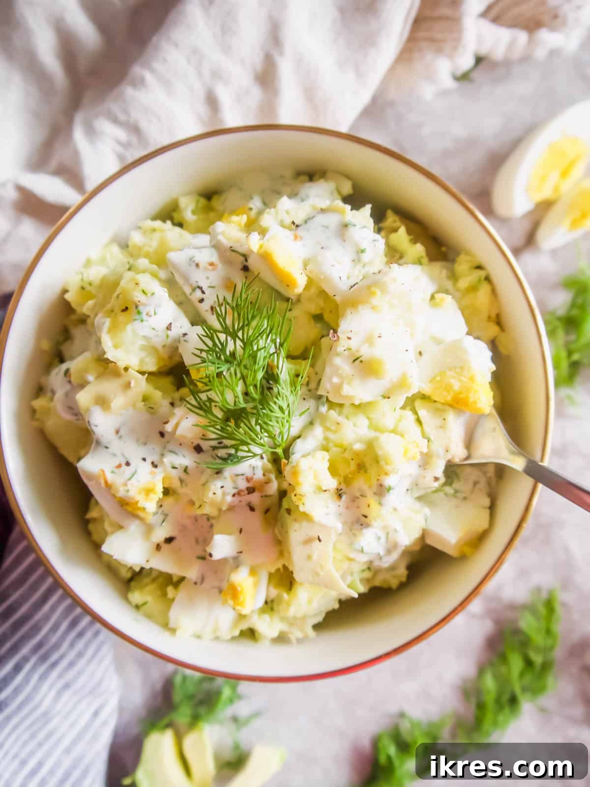 Close-up of healthy avocado potato salad in a bowl with a serving spoon.