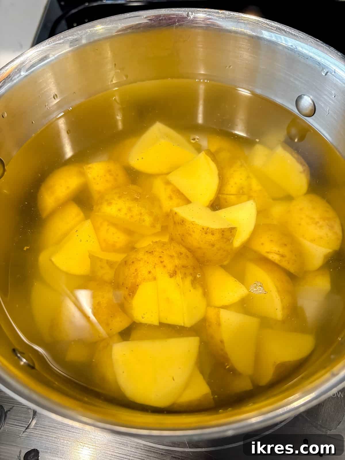 Potatoes boiling in a pot on the stovetop.