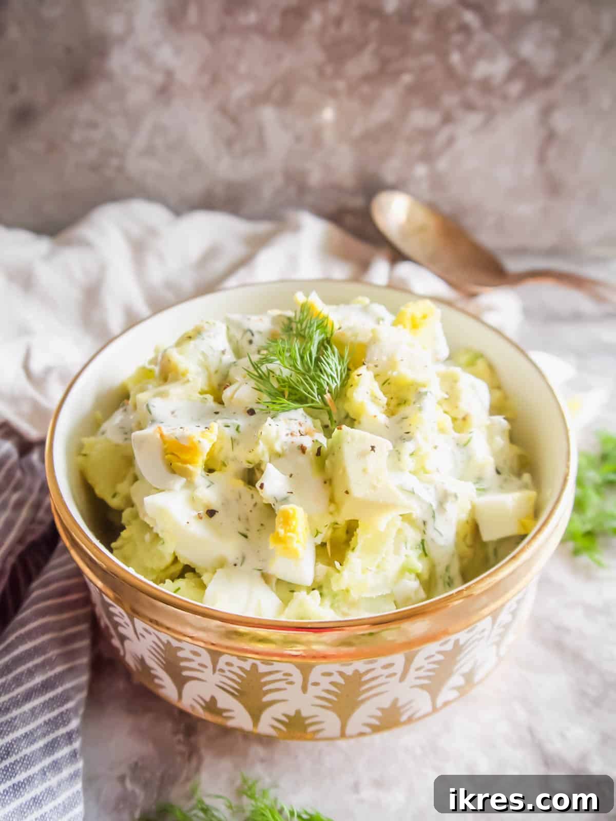 Homemade egg potato salad with avocado, garnished with fresh dill.
