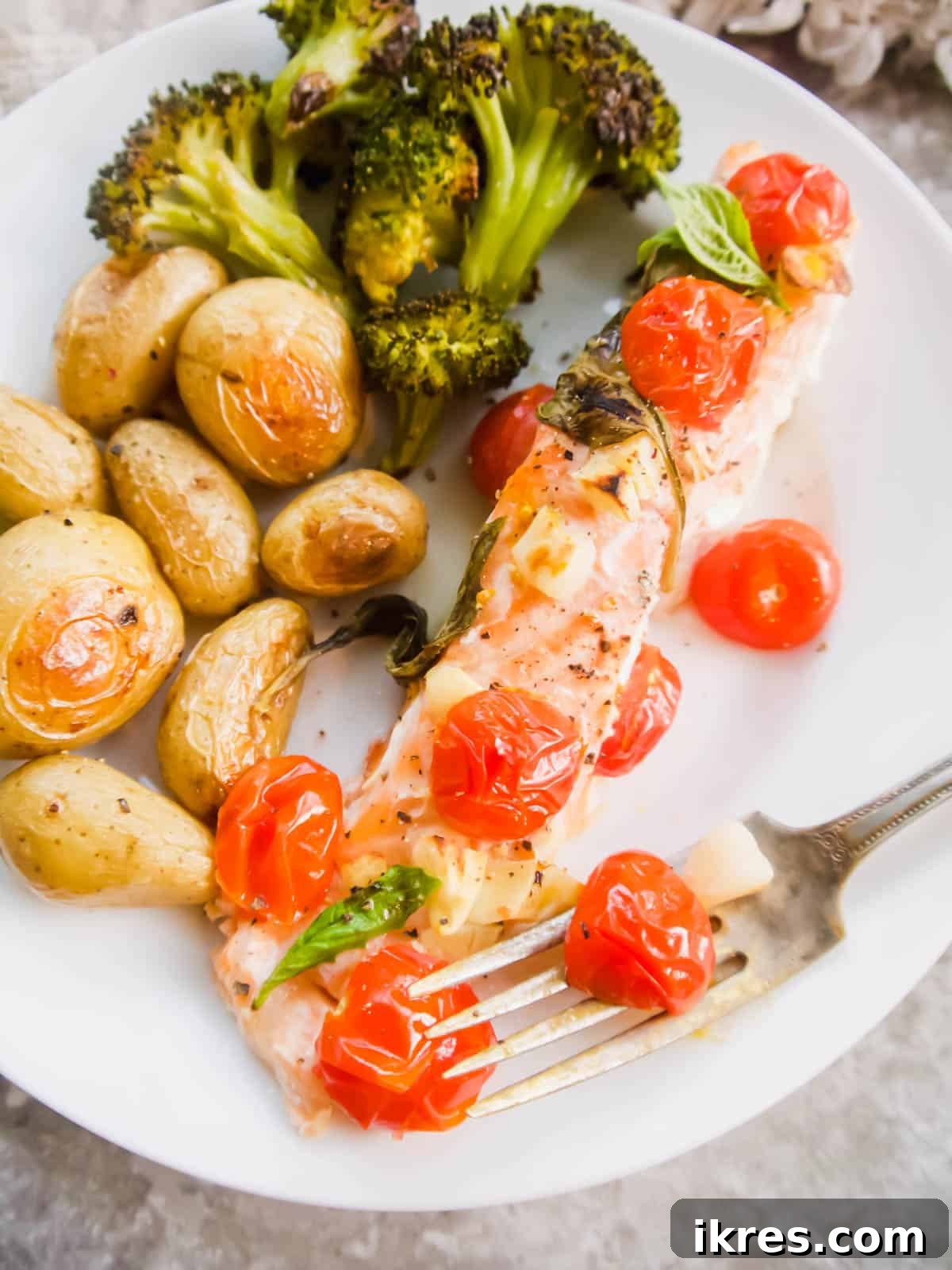 Basil Tomato Salmon Foil Packets 3 Salmon and tomatoes on a plate with roasted potatoes and greens