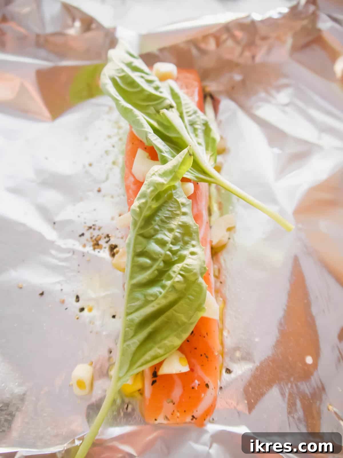 Basil Tomato Salmon Foil Packets 6 Salmon with garlic and fresh basil leaves on top.